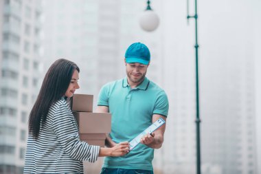Delivery man wearing cap giving declaration to customer