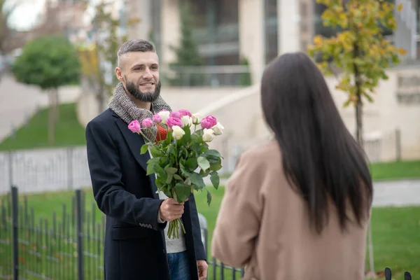 Bärtiger junger Mann kommt zu einem Date mit Blumen — Stockfoto