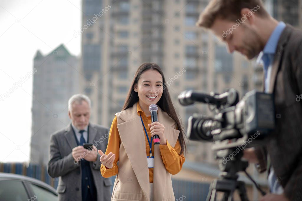 Young cute female reporter talking to a videocamera