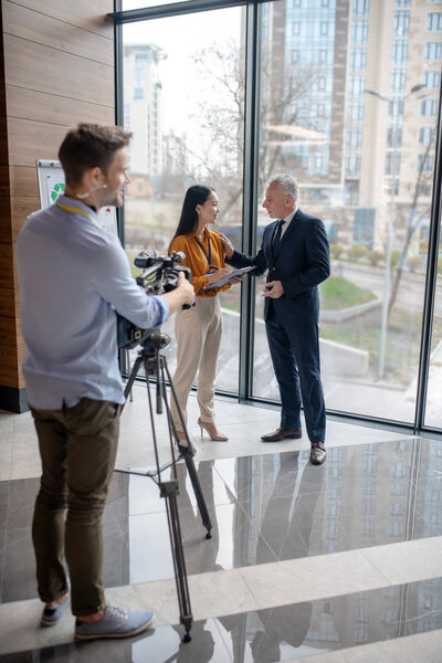 Young asian reporter talking to a grey-haired man