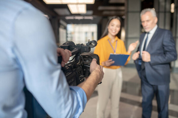 Asian female reporter in beige pants smiling nicely