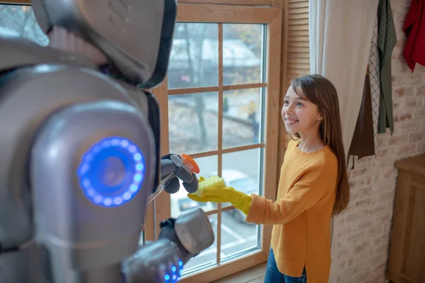 Robot og ei søt jente som gjør husarbeid sammen – stockfoto