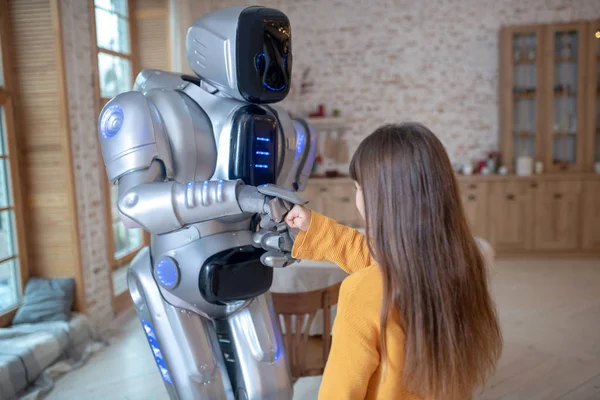 Turuncu gömlekli kız ve robot birlikte vakit geçiriyor. — Stok fotoğraf