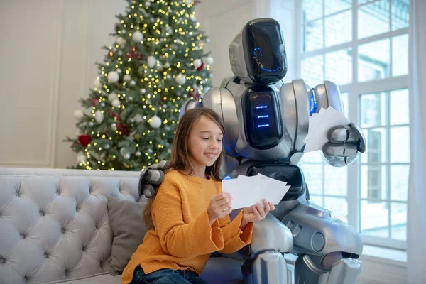 Pretty smiling girl showing photos to robot — Stock Photo, Image