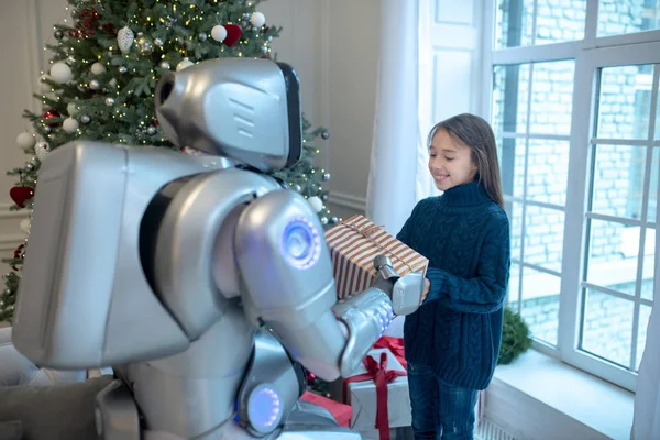 Pretty girl getting a christmas gift from her robot friend — Stock Photo, Image