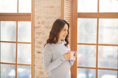 Ellerinde fincanla pencerenin yanında duran güzel Yuoung kadını.