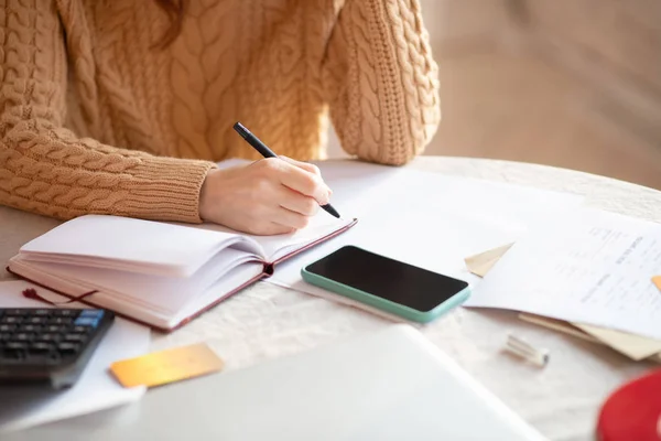 Donna dai capelli scuri in maglia maglione scrittura nel suo taccuino — Foto Stock