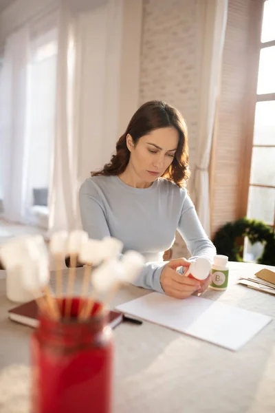 Young cute woman in grey homewesarsitting at the table at home — Stok fotoğraf