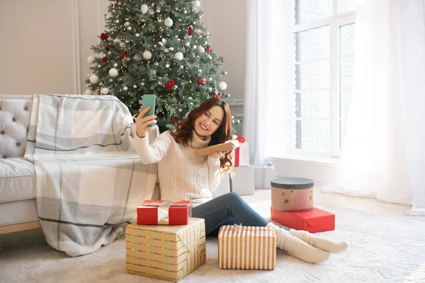 Dark-haired woman making photos with christmas gifts — Stock Photo, Image
