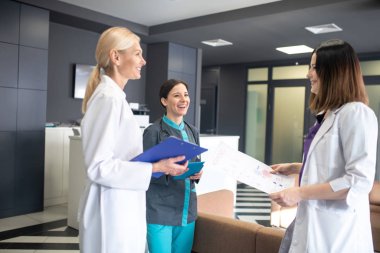 Koridorda konuşan üç kadın doktor.