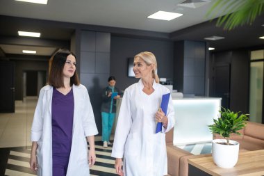 Beyaz cüppeli iki kadın doktor birbirlerine bakıyorlar.