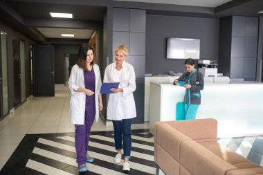 Klinik koridorunda yürüyen iki kadın doktor.