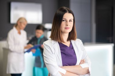 Beyaz cüppeli güzel, siyah saçlı doktor ciddi görünüyor.