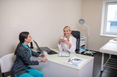 İki kadın doktor vardiyadan sonra klinikte sohbet ediyorlar.