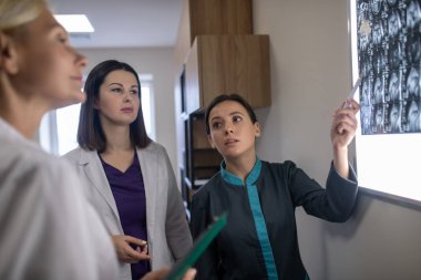 Üç kadın doktor MRI beyin taramasını tartışıyor.