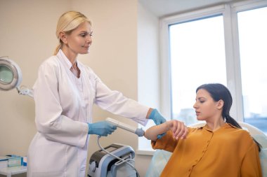 Steril eldivenli sarışın doktor hastayla çalışıyor.
