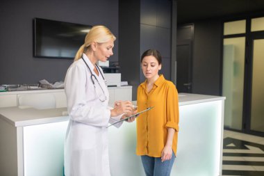 Beyaz cüppeli sarışın doktor ciddi görünüyor.