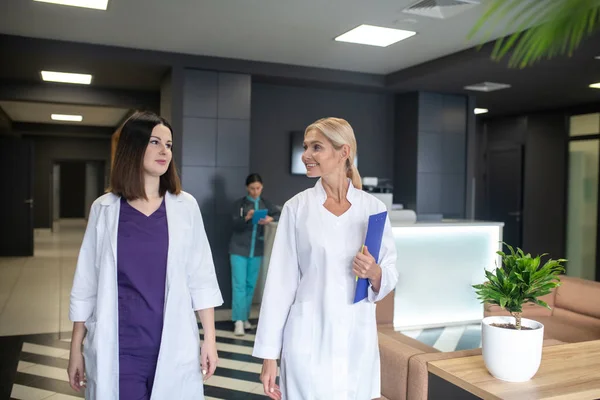 Két fehér köpenyes női orvos nézi egymást. — Stock Fotó