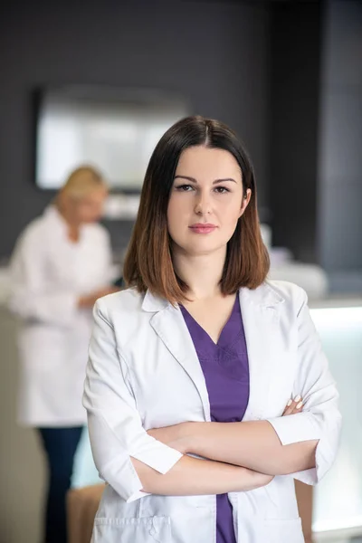 Beautiful dark-haired doctor in white robe looking confident — Stock Photo, Image