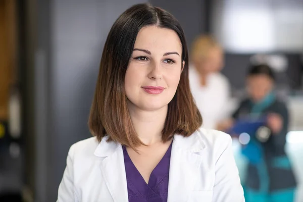 Beautiful dark-haired doctor in white robe looking thoughtful — Stock Photo, Image