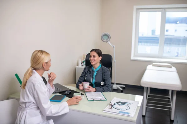 Twee vrouwen die een gesprek voeren in een lichte kamer — Stockfoto