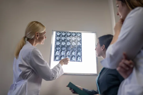 Médico loiro explicando ressonância magnética para seus colegas — Fotografia de Stock