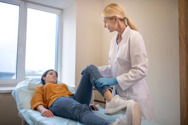 Médecin blond portant des gants stériles travaillant avec les patients jambe — Photo