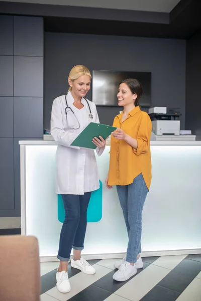 Blonde médecin aider en robe blanche debout dans le hall — Photo