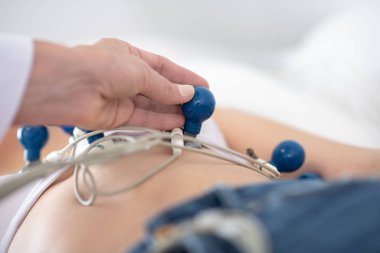 Beyaz cüppeli doktor hastaya EKG yapıyor.
