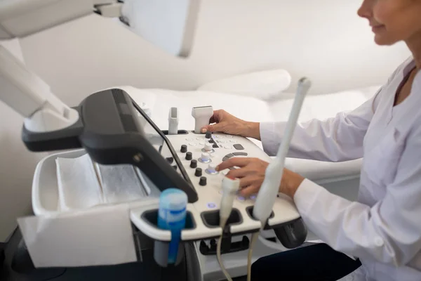 Rubio especialista en ultrasonido agradable en bata blanca en la máquina de ultrasonido — Foto de Stock