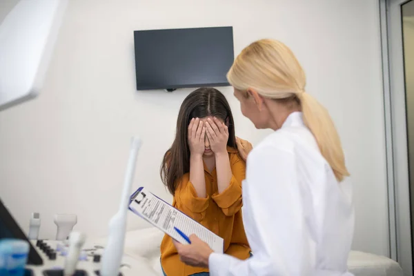 Paciente jovem do sexo feminino sentindo-se chateada no consultório doctots — Fotografia de Stock