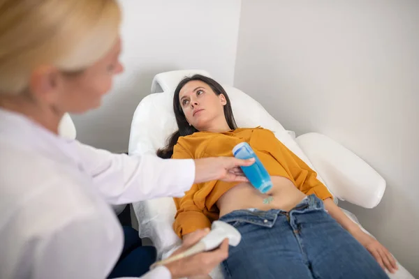 Médico femenino que aplica gel para procedimiento de ultrasonido en el vientre de los pacientes — Foto de Stock