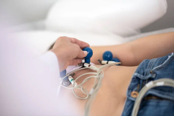 Lege i hvit kappe som fester elektroder til pasientene bryst – stockfoto
