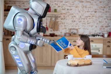 Robot bir kıza İngilizce dil bilgisi kitabı veriyor.
