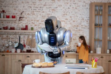 Elinde not defteri olan robot ev ödevlerini kontrol ediyor.