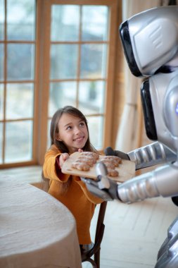Önlüklü ev robotu akşam yemeği için masaya servis yapacak.