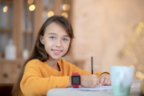 Schattig meisje in oranje shirt en smartwatch kijken positief — Stockfoto