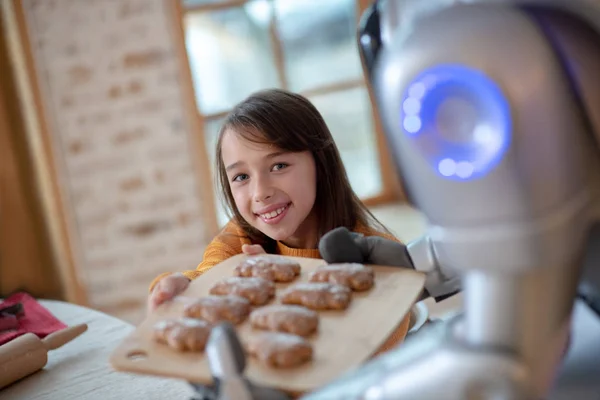 Smiling cute girl feeling good at home with house robot