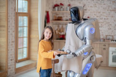 Önlüklü ev robotu vuruşun ortasında duruyor.