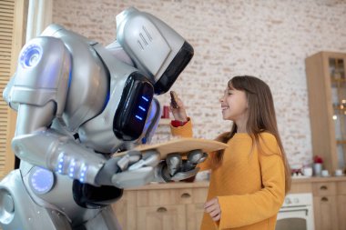 Ev robotunu besleyen uzun saçlı tatlı kız.
