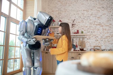 Ev robotu elinde köfteli tepsi tutuyor.