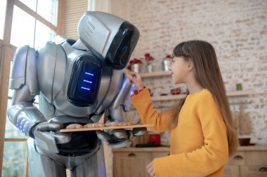 Ev robotu kıza köfte ikram ediyor.