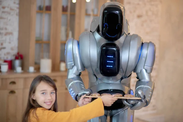 Şirin mavi gözlü kız ev robotu tarafından yapılan köfteleri gösteriyor. — Stok fotoğraf