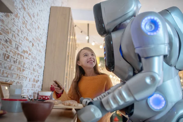 Pretty beaming girl looking at house robot — Stock Photo, Image