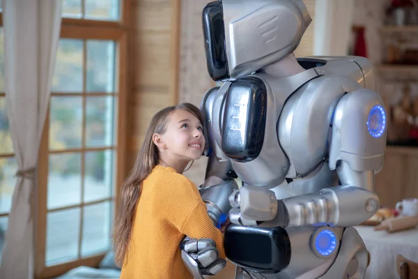 Turuncu tişörtlü tatlı kız ev robotuyla kendini rahat hissediyor. — Stok fotoğraf