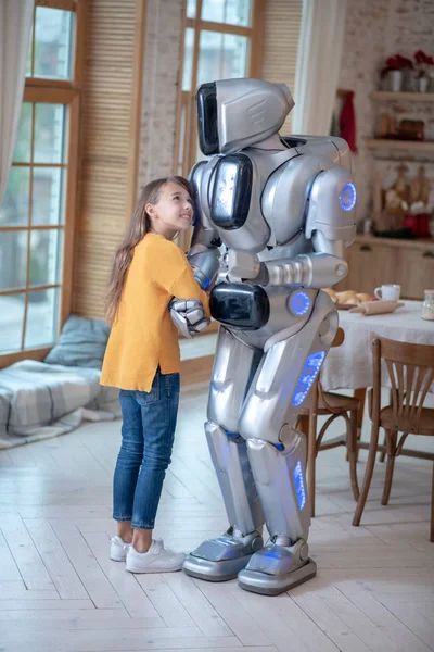 Turuncu tişörtlü kız ev robotuyla iyi hissediyor. — Stok fotoğraf