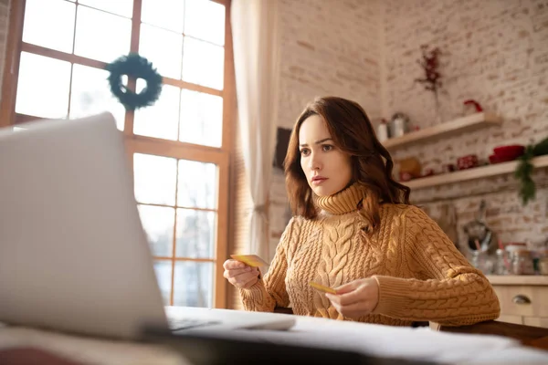 Mujer joven de cabello oscuro en suéter trabajando en una computadora portátil — Foto de Stock