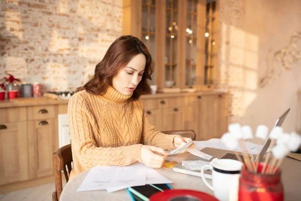 Woman in brown knitted sweater analyzing the bill — Stock Photo, Image