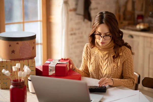 Mujer linda en gafas de vista sentada a la mesa con regalos — Foto de Stock