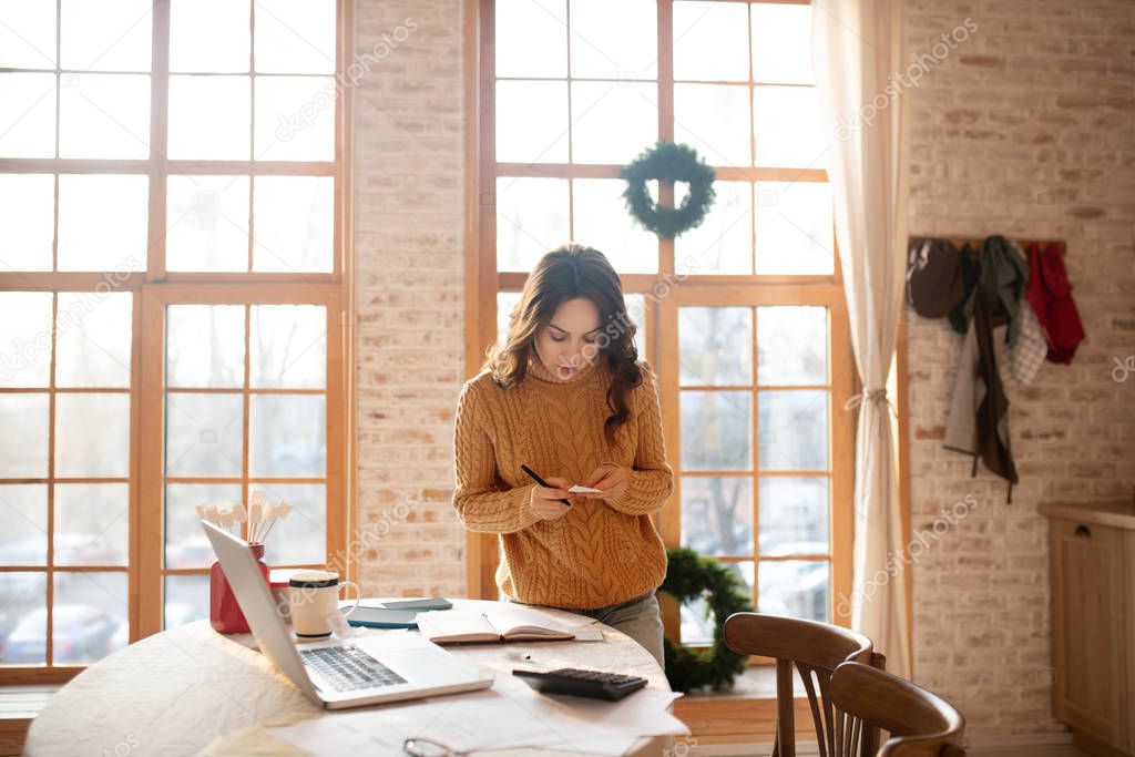 Dark-haired young woman in sweater working from home